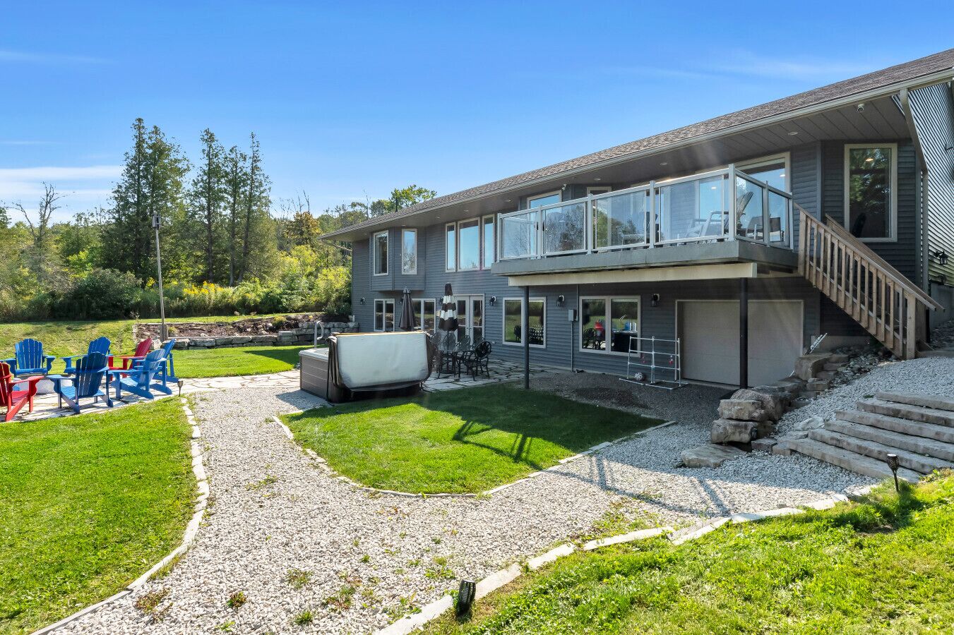 A modern two-story house with a covered patio, a stone pathway, and outdoor seating.