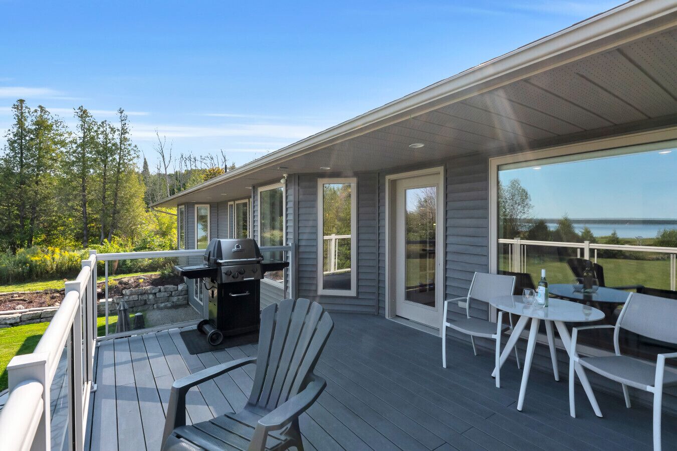 A deck with a grill, outdoor seating, and a view of the lake.