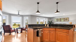 A spacious kitchen with a large island, wooden cabinets, and pendant lighting. - Scenic Waterfront 4BR – Hot Tub/Sleeps 12/Bonfire (Wiarton)