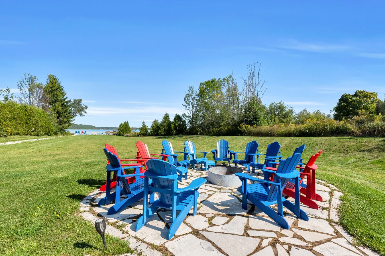 A circular seating arrangement with chairs around a fire pit on a stone patio.