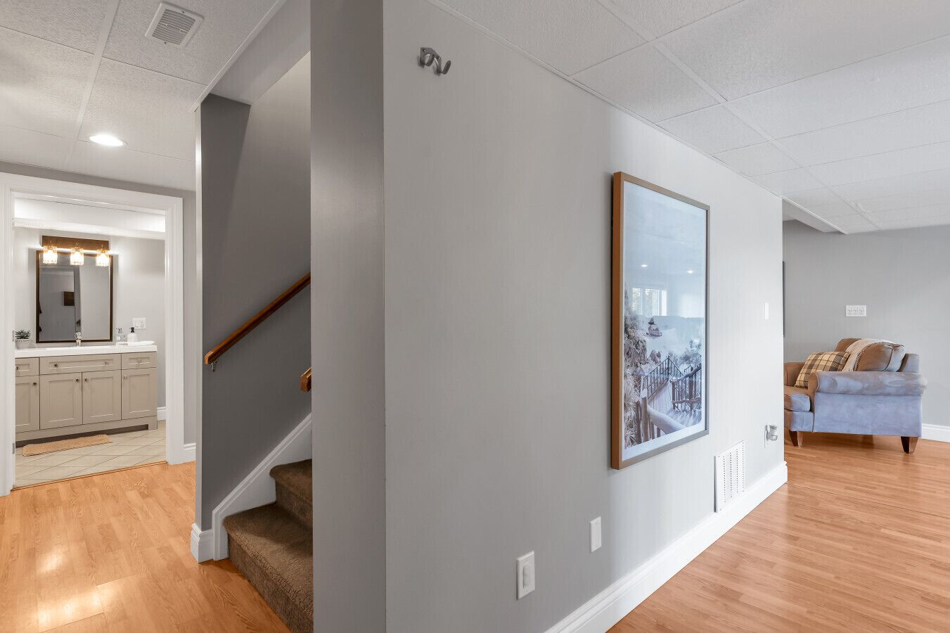 Interior moderno com escada, um quadro na parede e uma sala de estar com sofá.