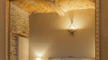 A bedroom with a large mirror, a bed, a nightstand, and a wall-mounted light fixture.