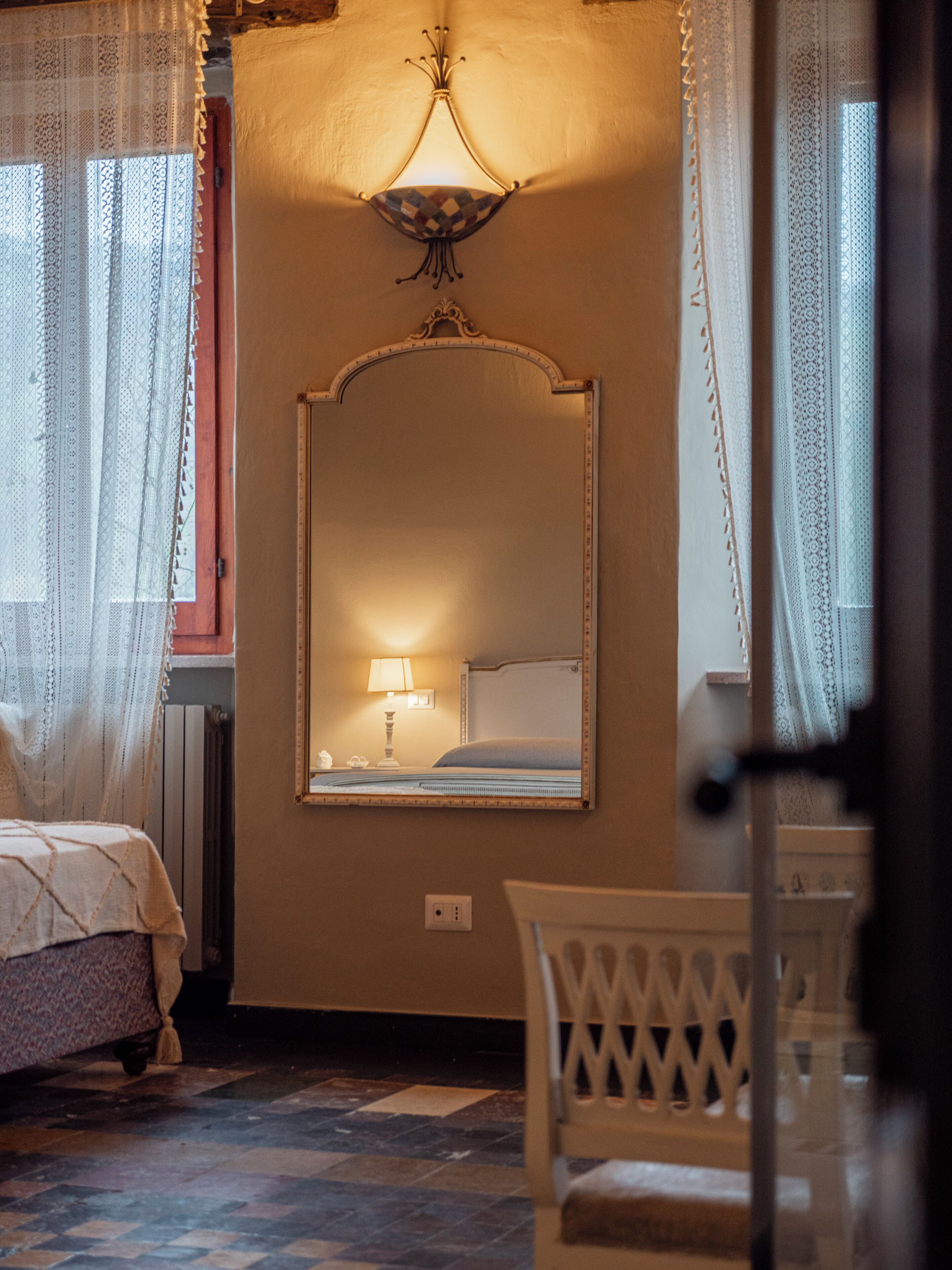 A bedroom with a large mirror, a bed, a nightstand, and a chair.