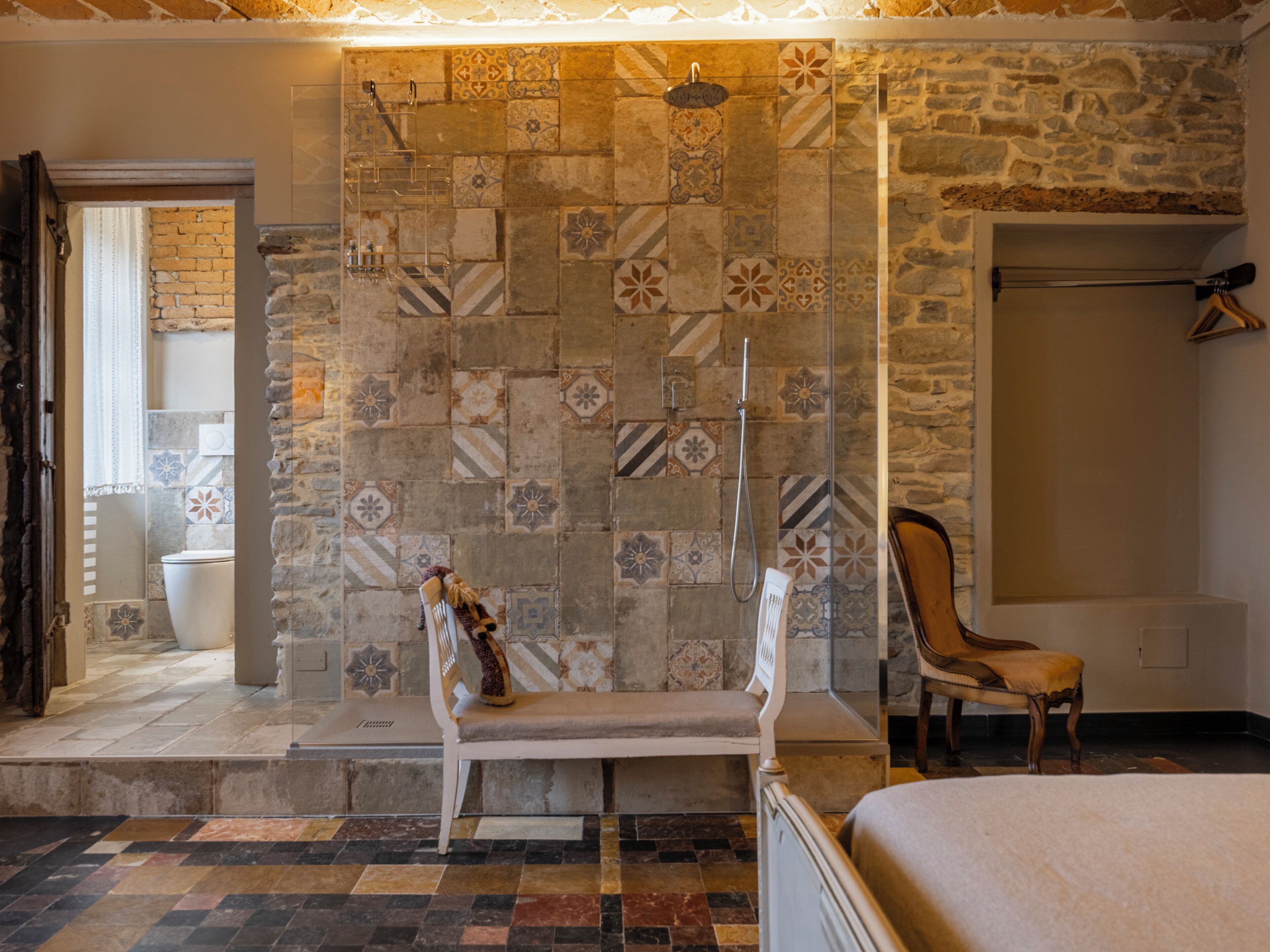 Een badkamer met een douche, een bankje en een stoel.