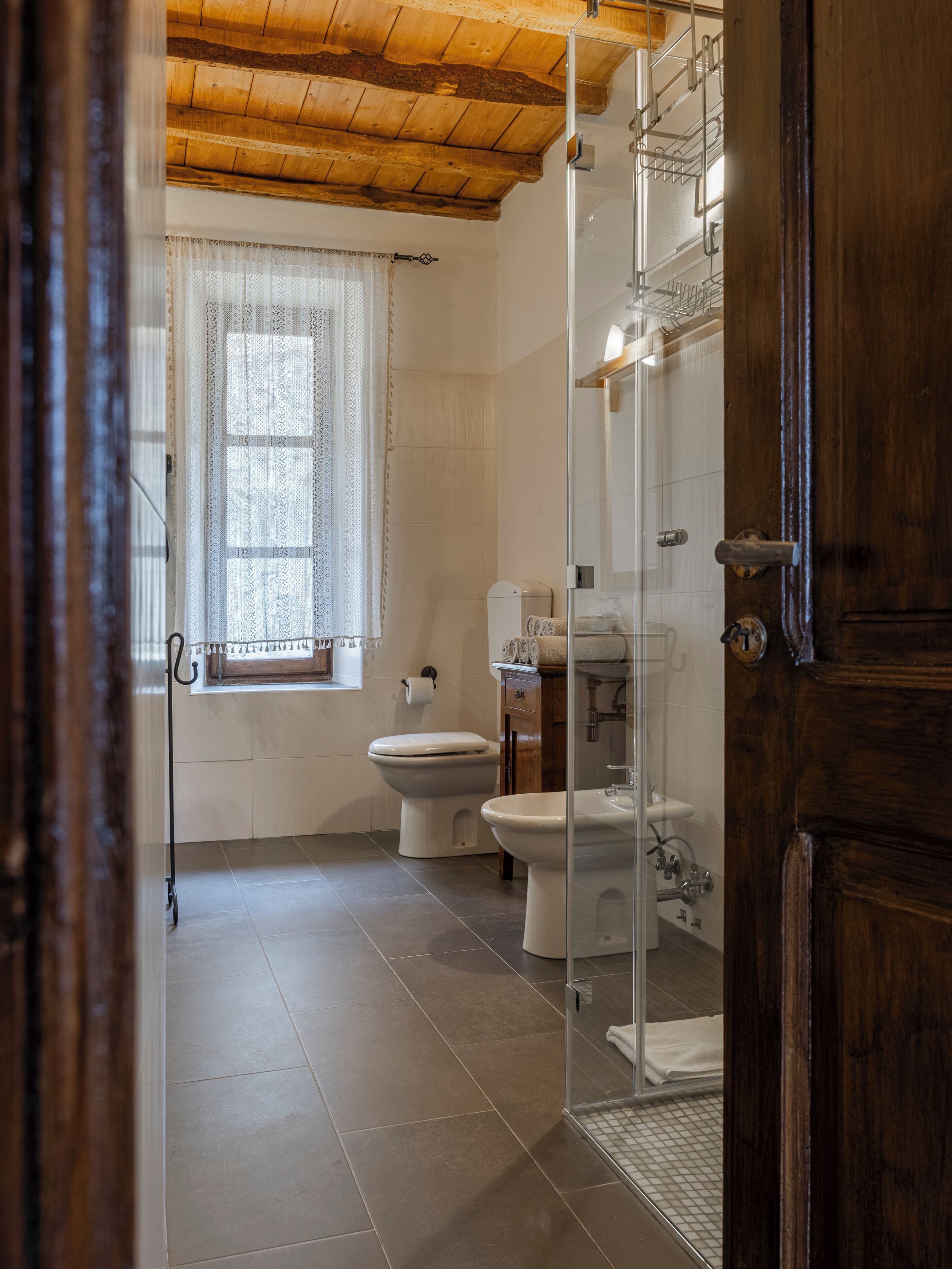 Un baño con inodoro, bidé y cabina de ducha de vidrio.