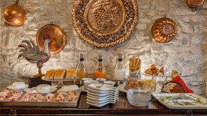 A buffet with various food items, including meats, cheeses, and pastries, arranged on a wooden counter against a stone wall. - Casa Levi (Bistagno)