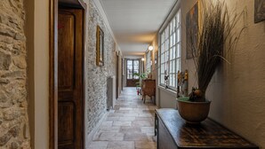 A stone-walled hallway with wooden doors and a bench. - Casa Levi (Bistagno)
