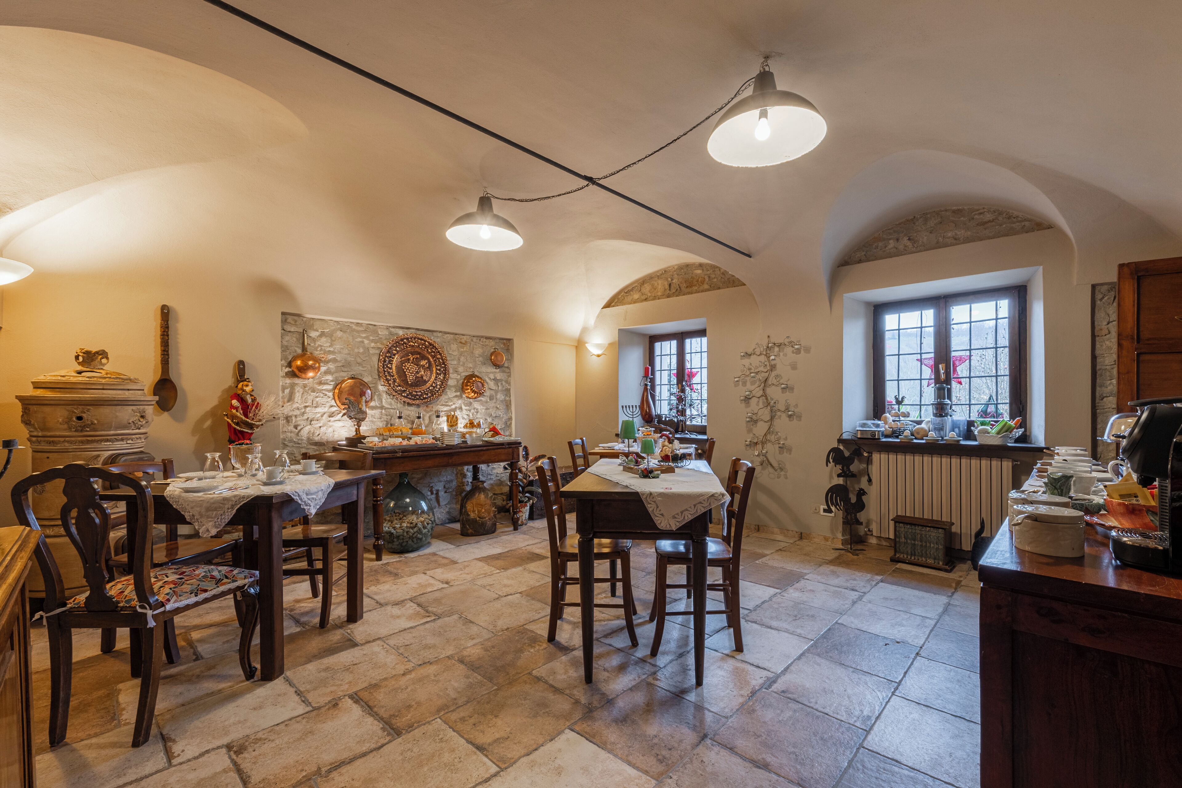 A dining area with a stone floor, wooden tables, and chairs. There are decorative items on the walls and a window with a view.