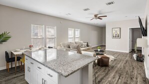 Un apartamento moderno con una isla de cocina, una sala de estar con sofá y un comedor con mesa y sillas.