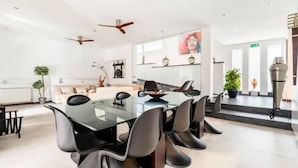 A modern dining area with a glass table, black chairs, and ceiling fans.