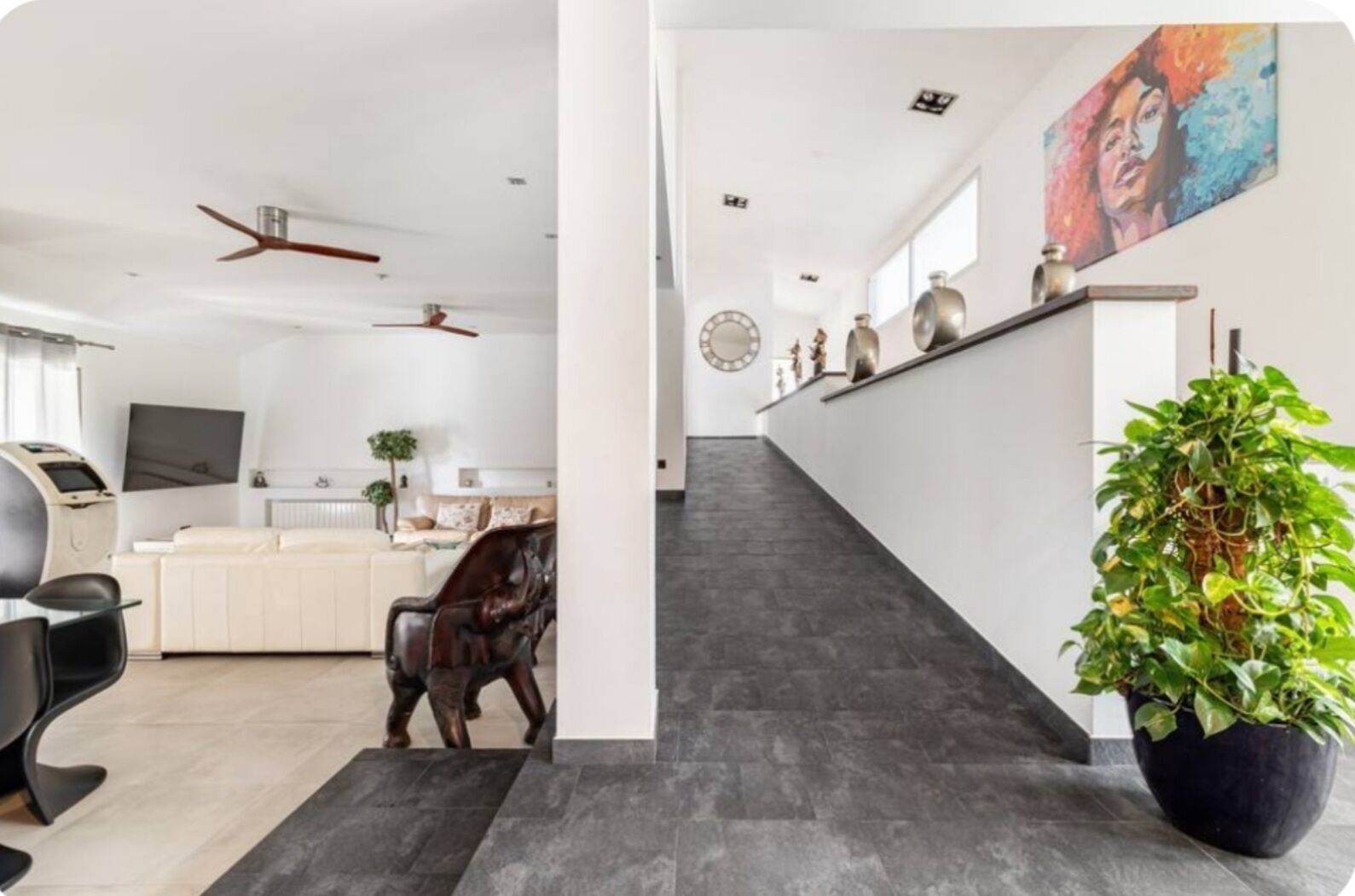 Een moderne woonkamer met een bank, een salontafel en een televisie. Er is een trap die naar een hoger niveau leidt.