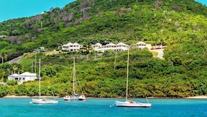 A coastal area with several white buildings on a hillside, boats in the water, and lush greenery. - A Yacht Haven (Christiansted)