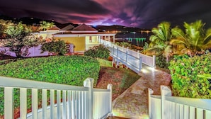 A hotel with a well-lit outdoor area, a staircase, and a view of the sea. - A Yacht Haven (Christiansted)