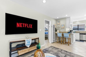 Ein modernes Wohnzimmer mit einem großen Flachbildfernseher, der 'NETFLIX' in roten Buchstaben anzeigt.