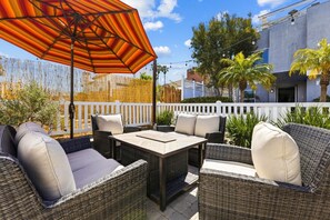 Une terrasse extérieure aménagée avec des meubles en osier, une table et un parasol.
