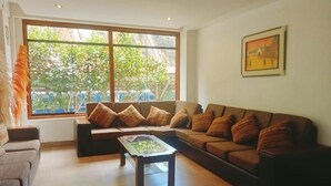 A living room with a large window, a sofa set, a coffee table, and a framed picture on the wall. - Hotel Seven Mapi Machupicchu (Machu Picchu)