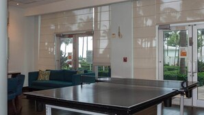 En lobby med et ping pong-bord, en blå sofa og en glasdør der fører udendørs.