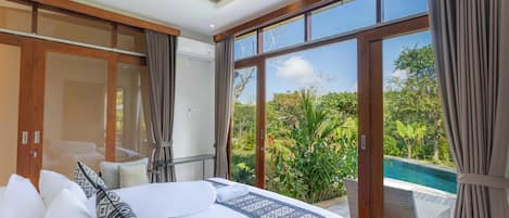 A bedroom with a large bed, a wardrobe, and a view of a swimming pool.