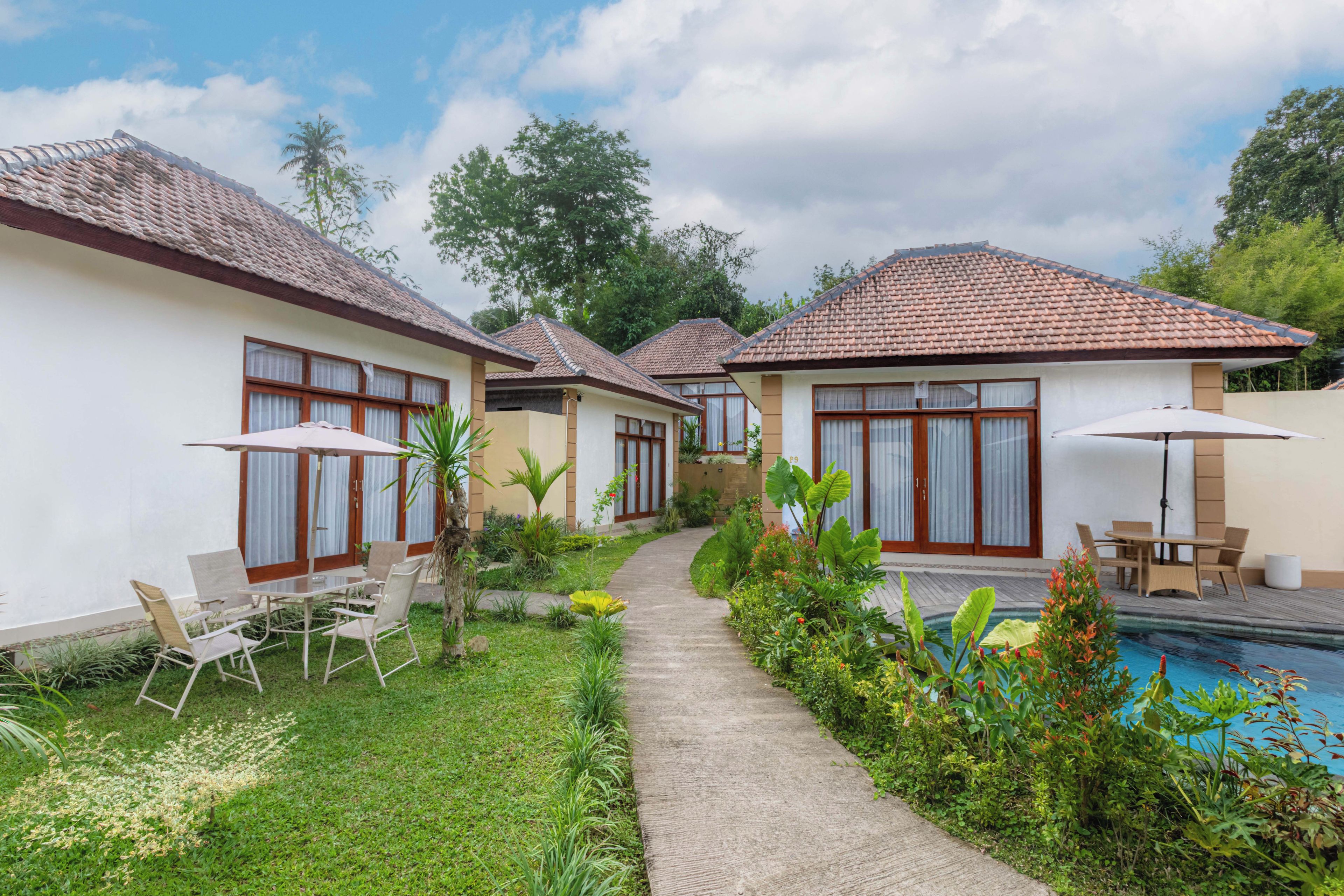 A row of single-story villas with tiled roofs, a swimming pool, and outdoor seating areas.
