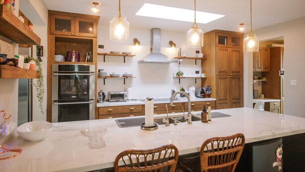 Una cocina moderna con armarios de madera, una isla central e iluminación colgante.