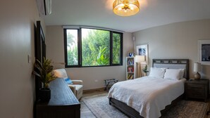 Un dormitorio con un ventanal grande, una cama, un escritorio y una silla.