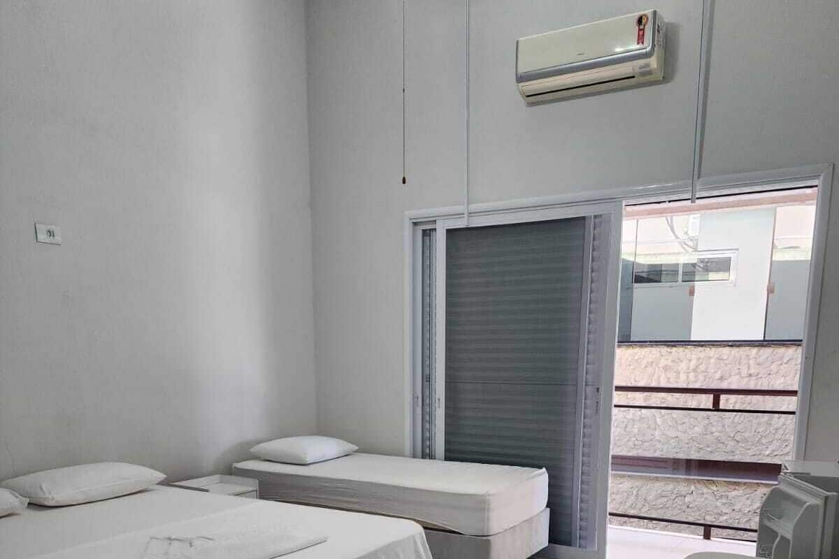 Una habitación con dos camas, una ventana y aire acondicionado.