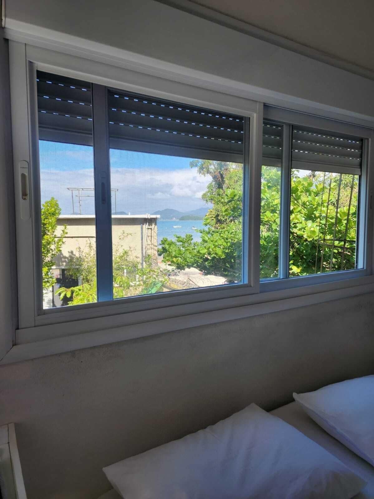 A room with a large window offering a view of a body of water and greenery.