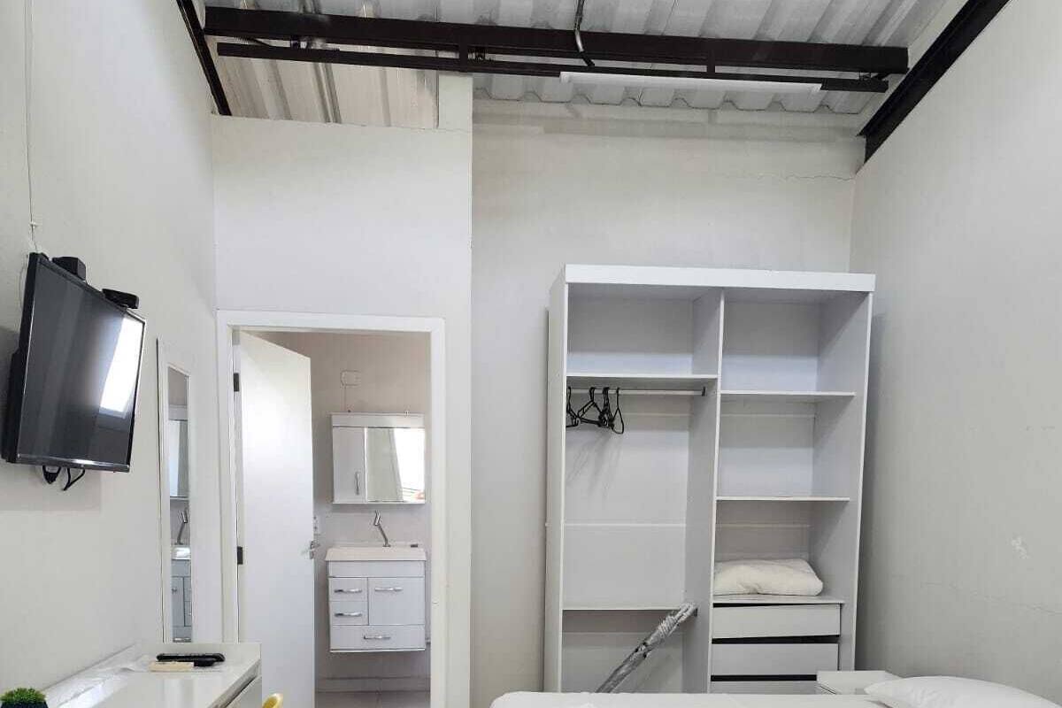 Un dormitorio con cama, escritorio, televisor y armario.