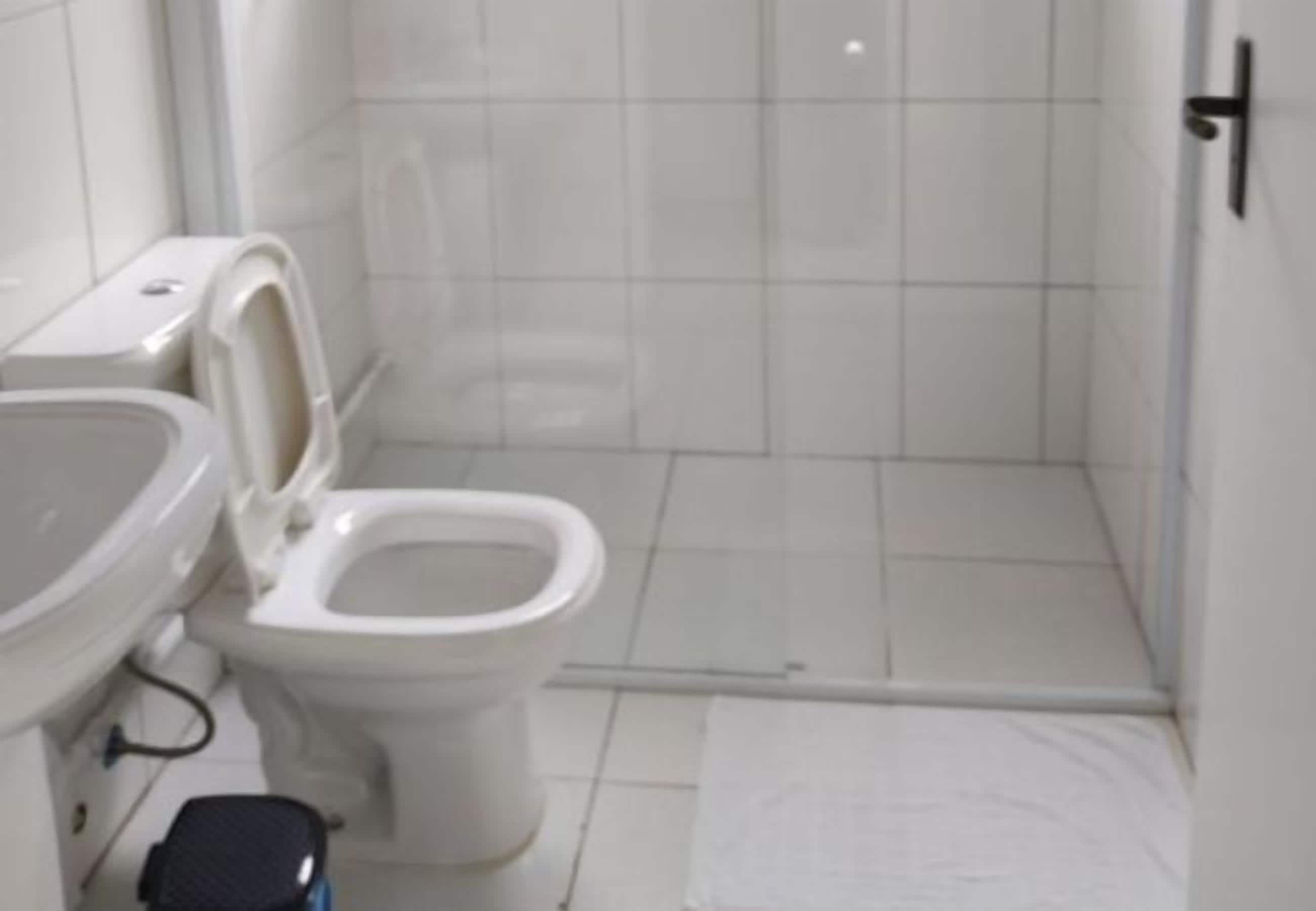 A small bathroom with a toilet, a sink, and a shower area.