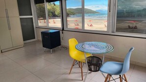 Ein Zimmer mit Blick auf den Strand, ein kleiner Tisch mit Stühlen und ein Schrank.