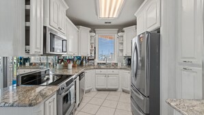 A modern kitchen with white cabinetry, stainless steel appliances, and a large window. - Pelican Point Bay on the Water, Boat Slips, View! (Port Isabel)