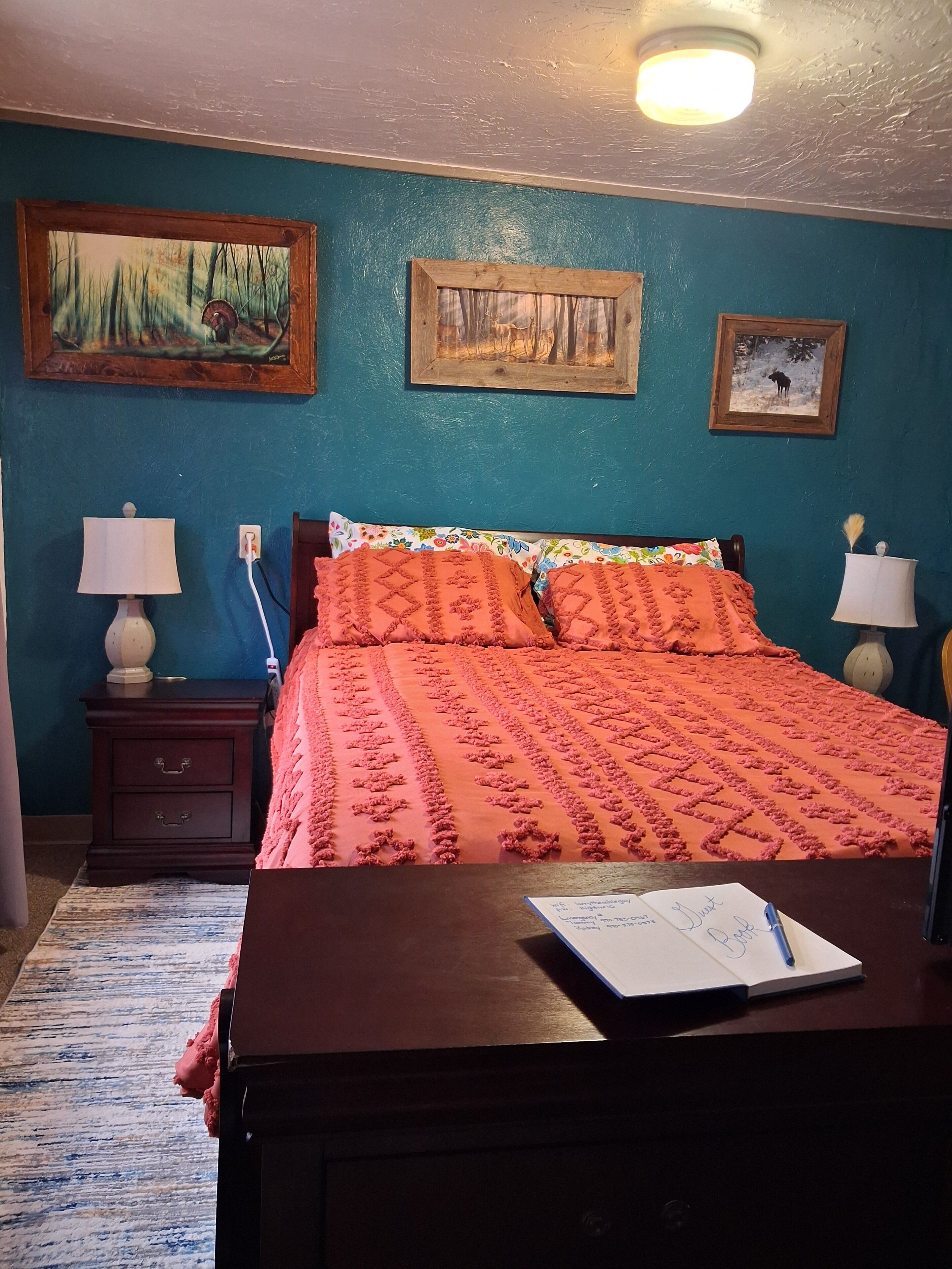Une chambre à coucher comprenant un lit, deux tables de chevet, une commode et trois tableaux encadrés accrochés au mur.