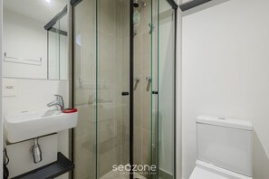 A modern bathroom with a glass-enclosed shower, a white sink with a red soap dish, and a white toilet. - Your Complete Stay in a Building With a Pool Just Steps From the Subway - FRE (São Paulo)
