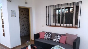 Ein Wohnzimmer mit einer Couch, einem Couchtisch und einem Fenster mit Metallgitter.