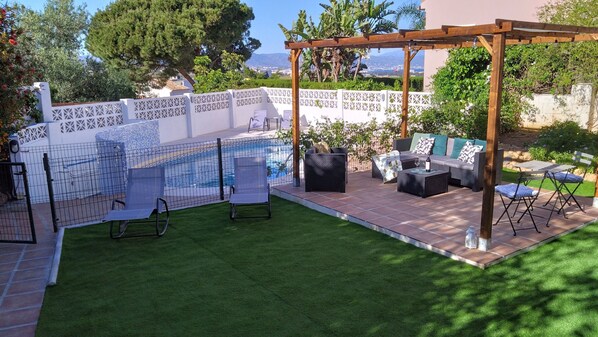 A backyard with a pool, outdoor furniture, and a pergola.
