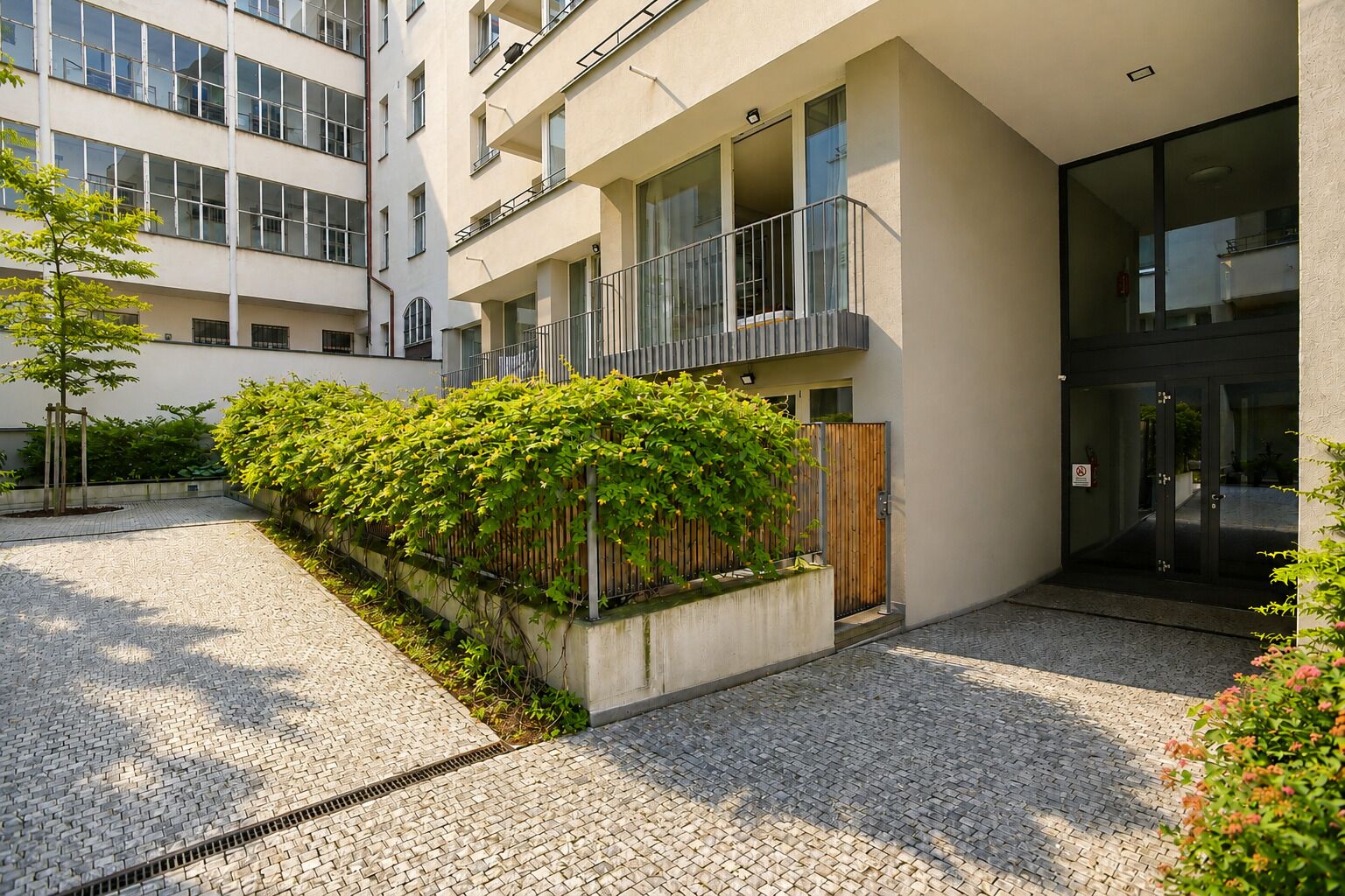 Un edificio moderno con un patio, cerca de madera y portón de metal.