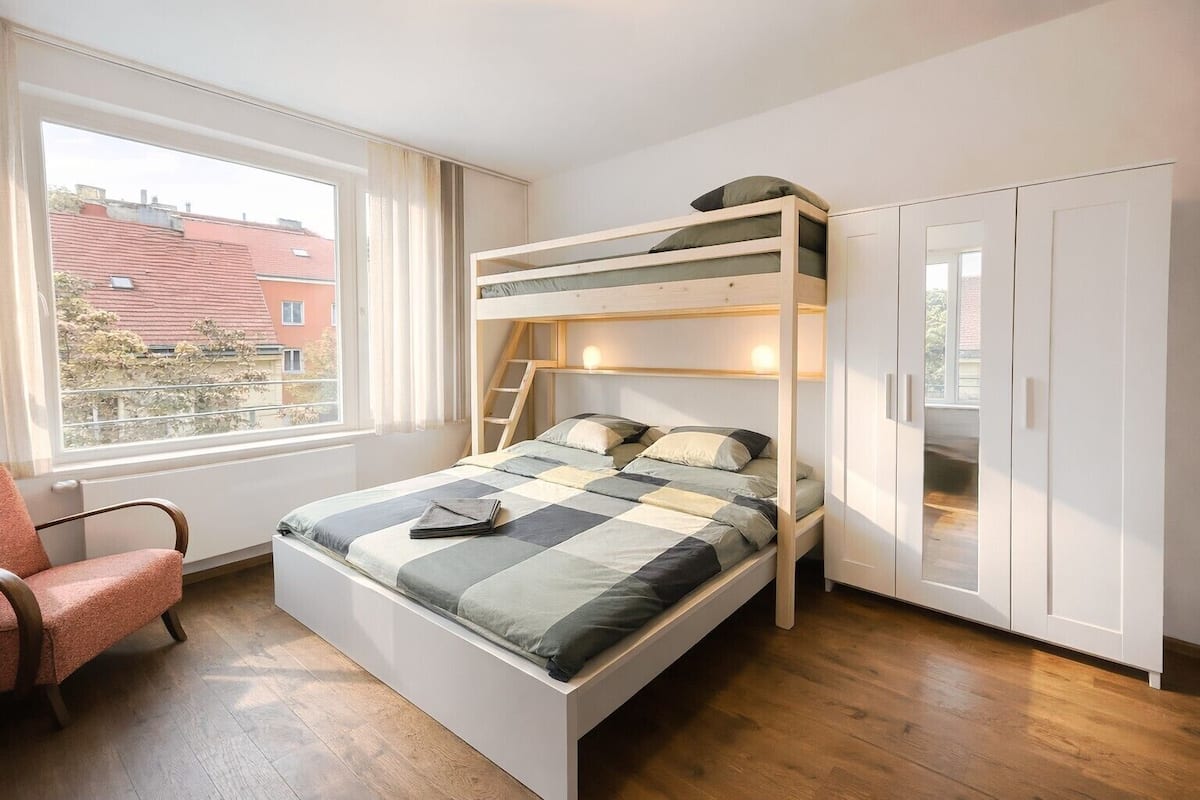Ein Schlafraum mit Etagenbetten und Blick auf Gebäude, ein Stuhl und ein Kleiderschrank.