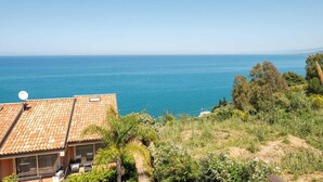 A coastal property with a tiled roof, a satellite dish, and a view of the sea.