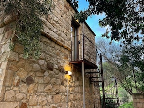 A stone building with a balcony and a spiral staircase.