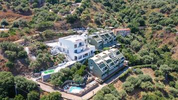 A modern villa with a pool, surrounded by dense vegetation and hills.