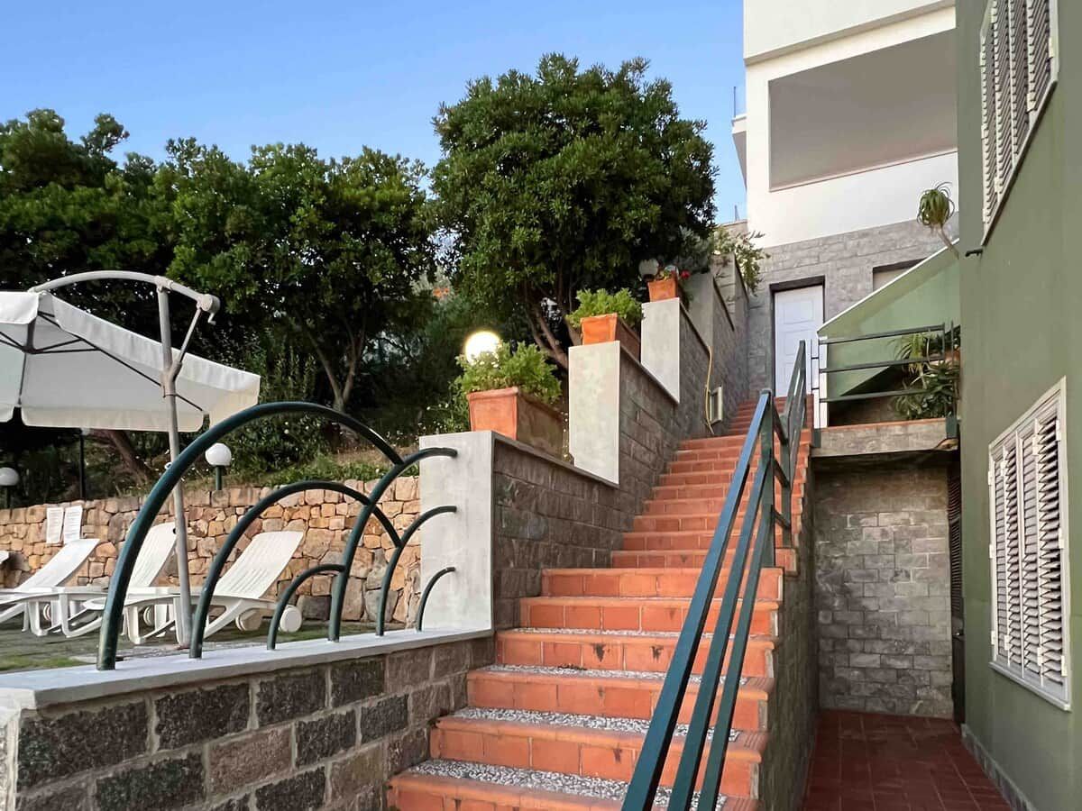 Un escalier menant à un espace piscine équipé de chaises longues et d’une rambarde.
