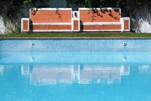 A swimming pool with clear blue water, surrounded by a tiled edge and a brick wall with white trim. - House A: 4 Suites |Pool Garden Sauna Tennis (Seixal)