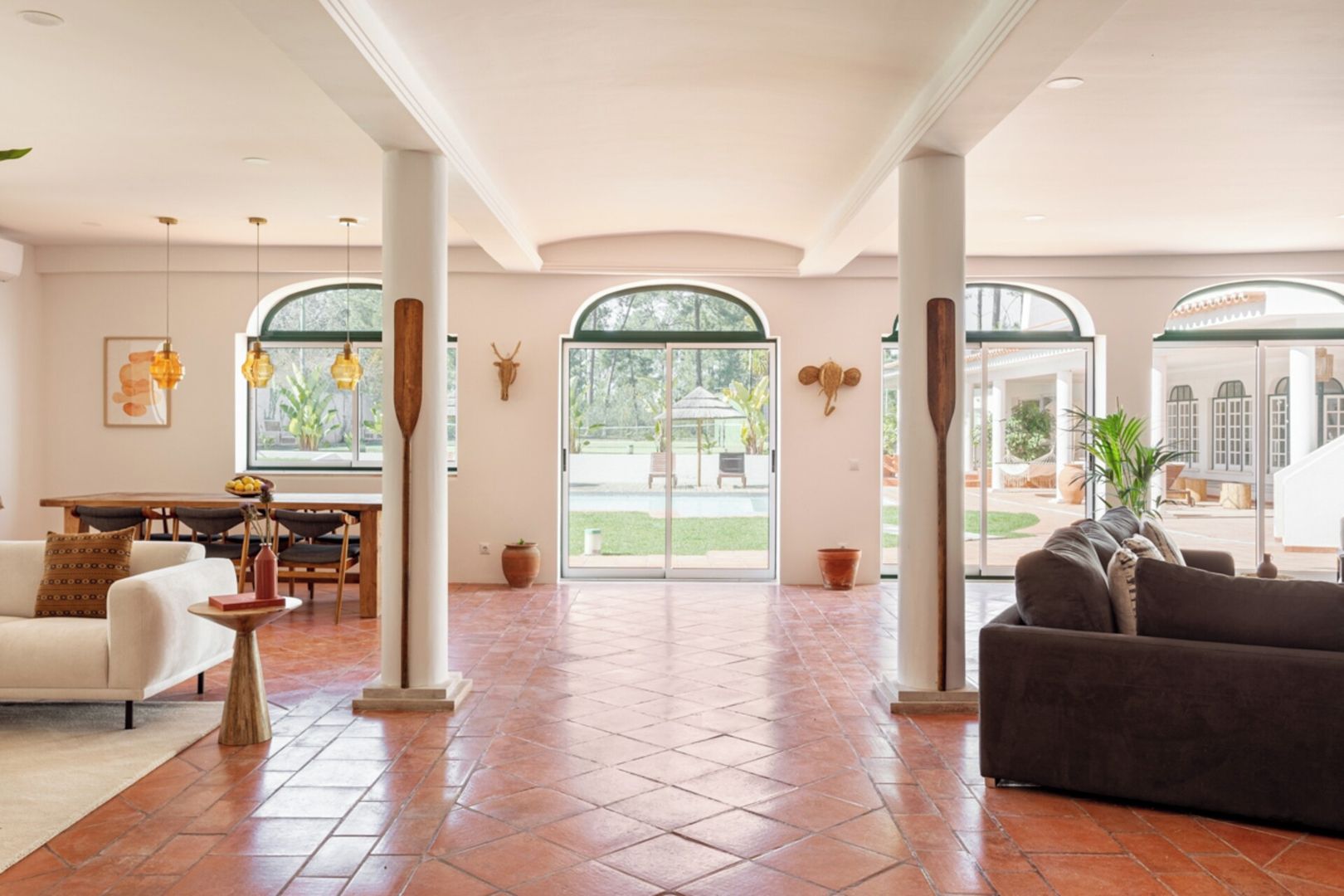 A spacious living area with a large window, a dining table, and a sofa.