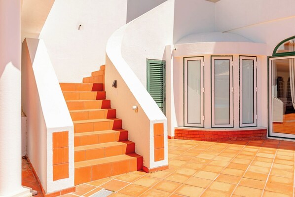 A staircase leading to a covered area with a tiled floor and a set of glass doors.