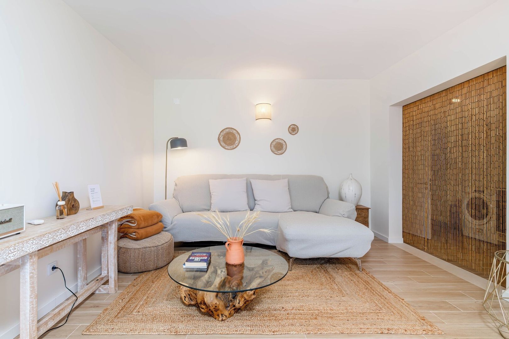 A modern living room with a sofa, a glass coffee table, and a decorative wall.