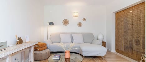 A modern living room with a sofa, a glass coffee table, and a decorative wall.
