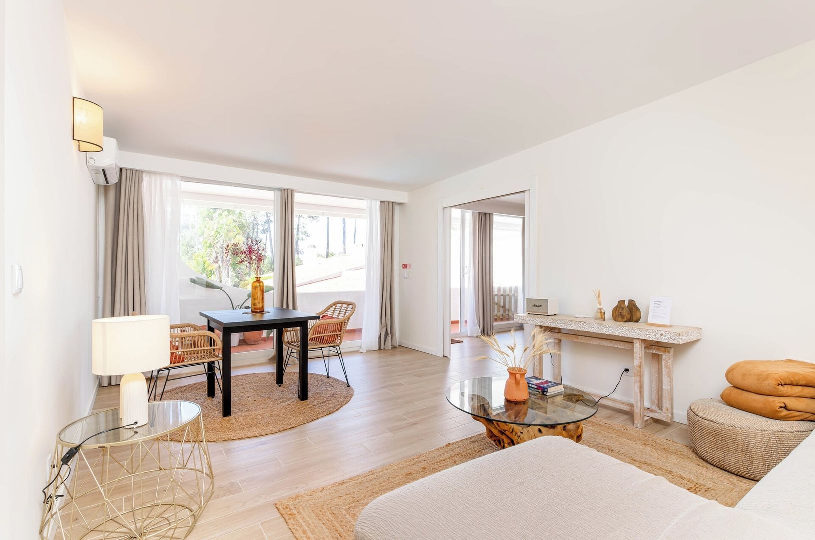 A modern living room with a glass coffee table, a sofa, a dining table with chairs, and a fireplace.