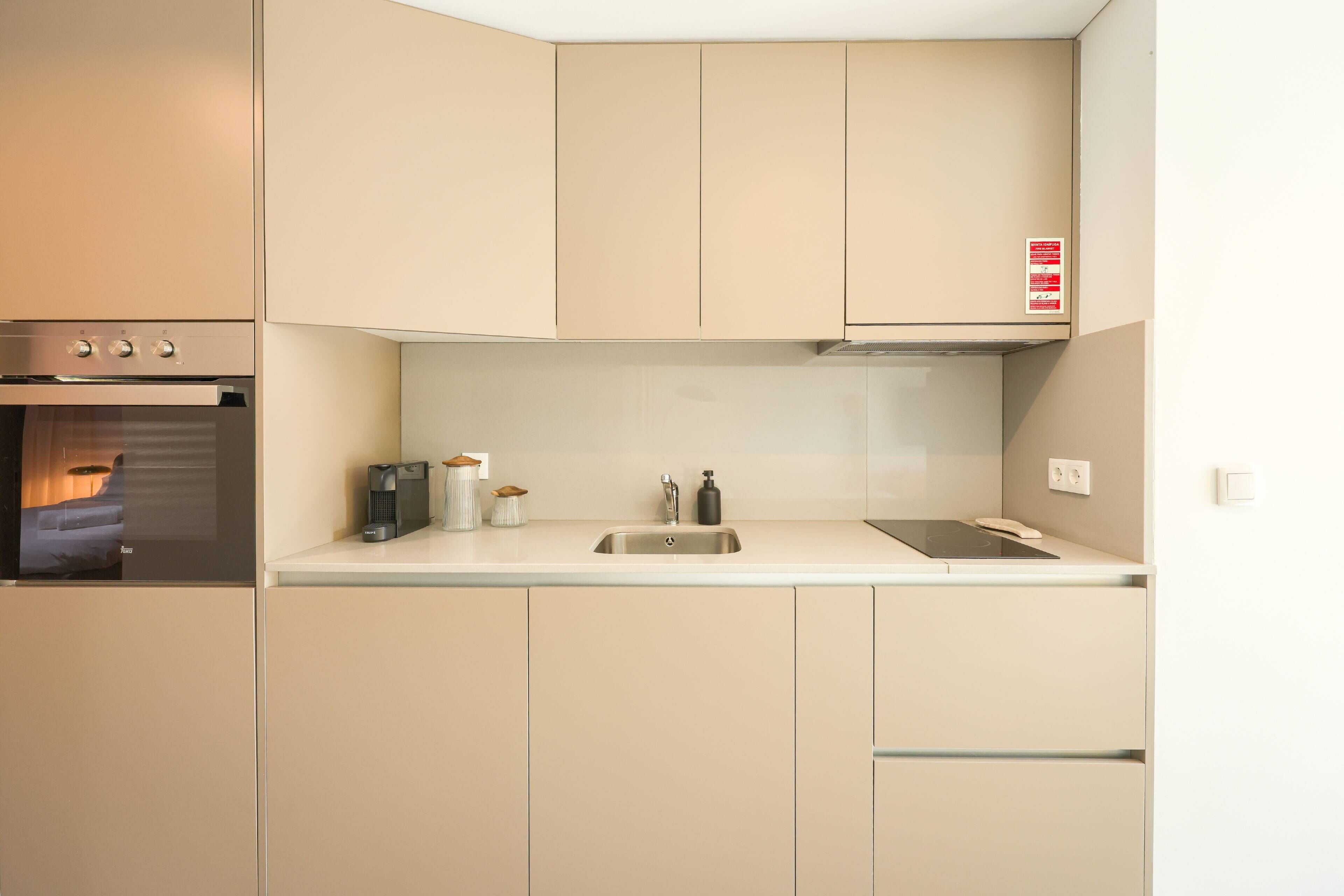 A compact kitchen with a built-in oven, a sink, and a stove.