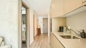 Uma cozinha moderna com pia de aço inoxidável, piso de madeira e vista para a sala de estar adjacente.