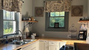 Una cocina con armarios blancos, encimera de madera, estufa negra y una lámpara colgante.